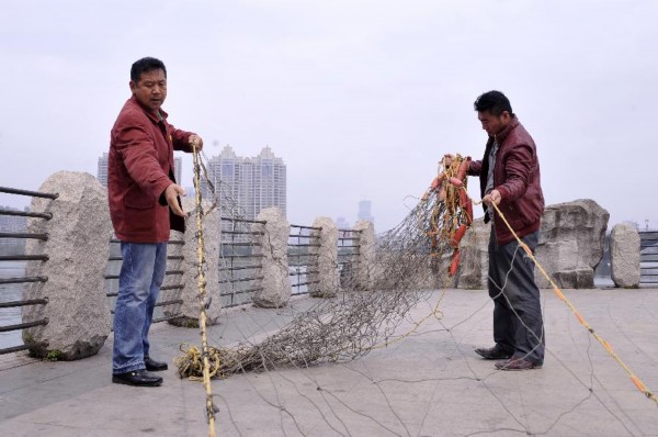 3月1日，赵喜昌（左）和救捞队队员马迎涛一起整理老赵亲手编织的救捞网。2011年，马迎涛曾因感情问题在惠州东江大桥跳江自杀，被赵喜昌救起后，2013年加入了老赵的救捞队。 新华社记者 梁旭 摄